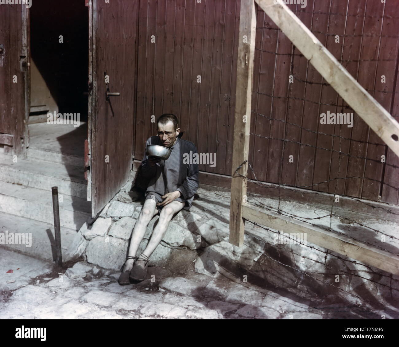 Zweiter Weltkrieg: Holocaust-Überlebende aus einer Metallschale vor Kasernen im KZ Buchenwald zu trinken. Stockfoto