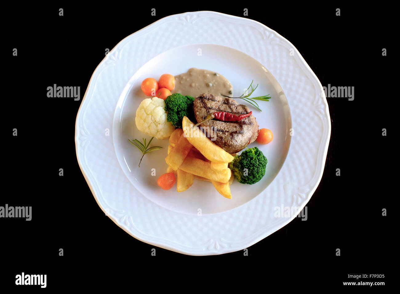 Rindersteak mit Bratkartoffeln und Gemüse im weißen Teller Stockfoto