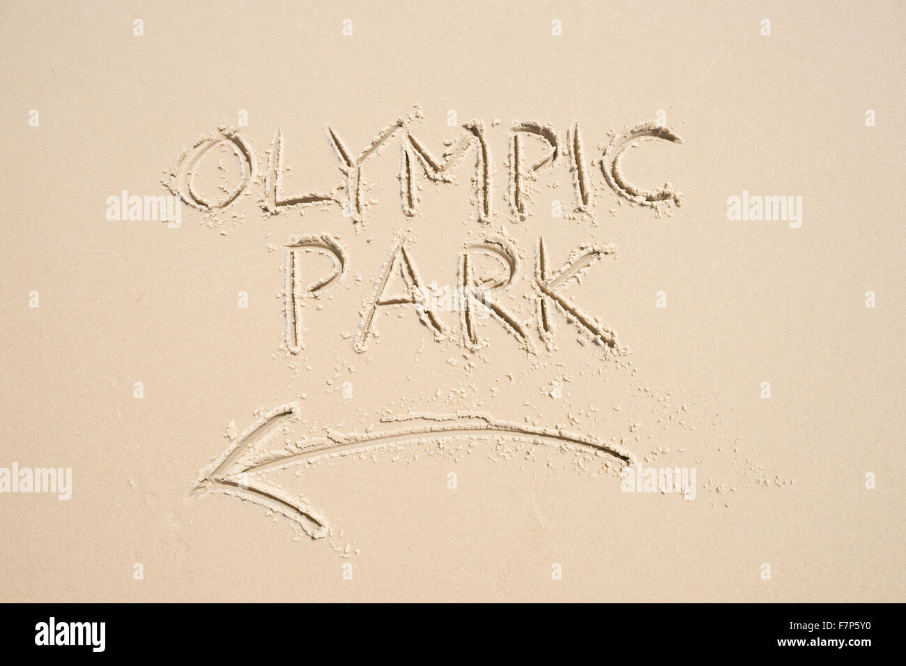 RIO DE JANEIRO, Brasilien - 10. November 2015: Handschriftliche Nachricht mit Pfeil weist uns den Weg zum Olympiapark in Sand geschrieben. Stockfoto