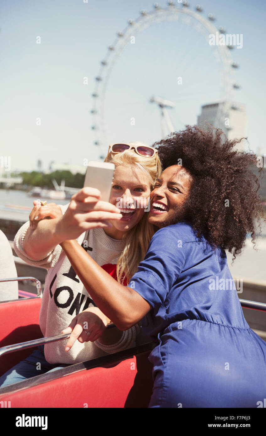 Begeisterte Freunde nehmen Selfie auf Doppeldecker-Bus mit London Eye im Hintergrund Stockfoto