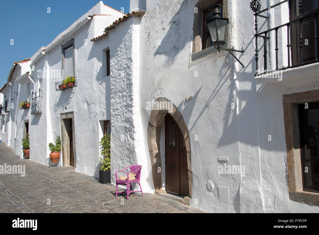 typische Straße in Monsaraz mit weißen Häusern und rosa Stuhl und Blumen in der Stadt Stockfoto