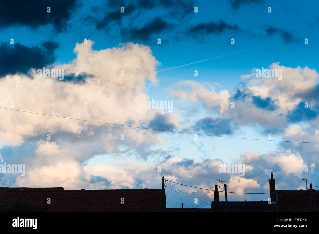 Ein stürmischer, bewölkten Himmel bei Sonnenuntergang in Norfolk mit der Hausdächer als Silhouetten. Stockfoto