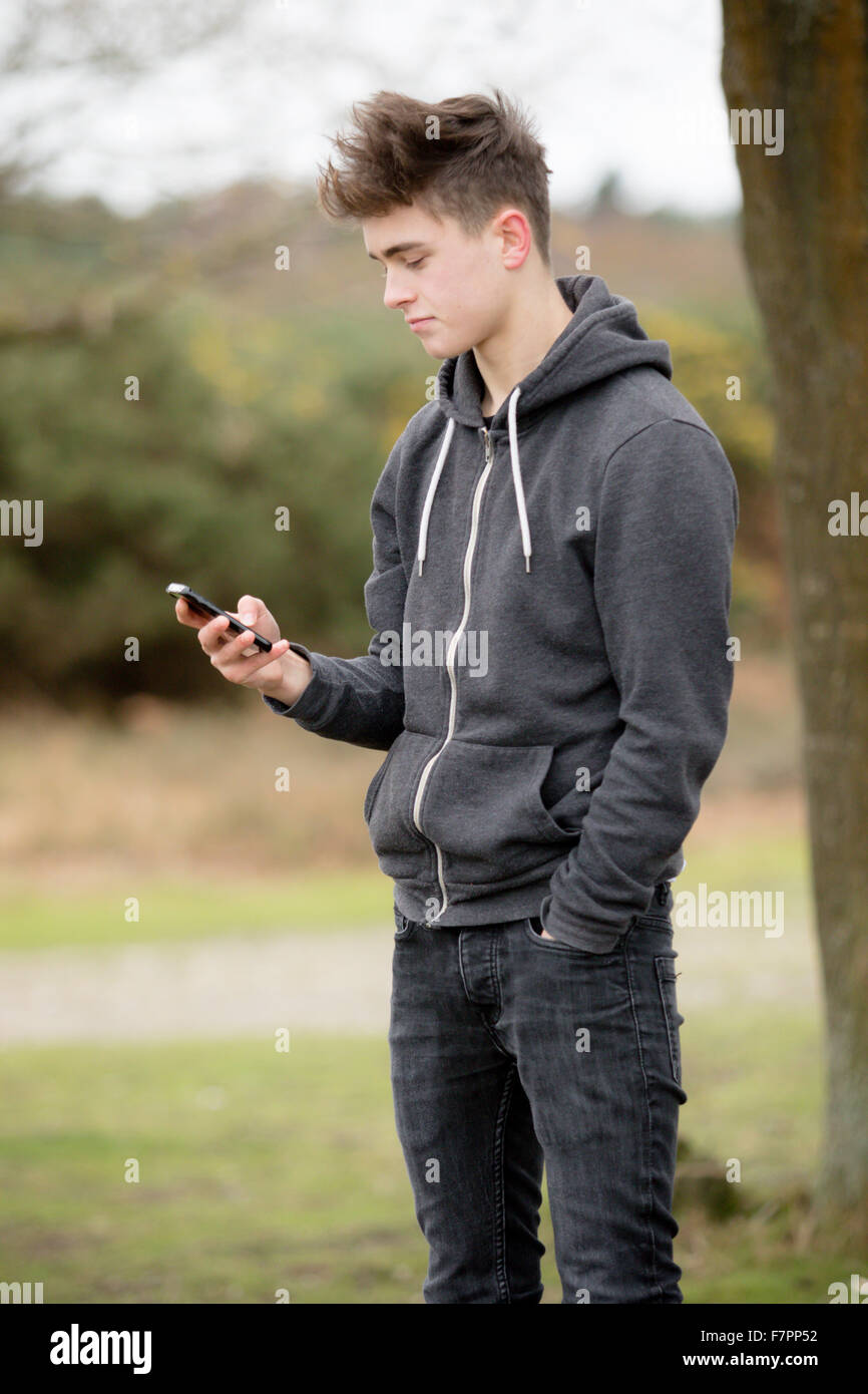 Teenager mit seinem Handy im freien Stockfoto