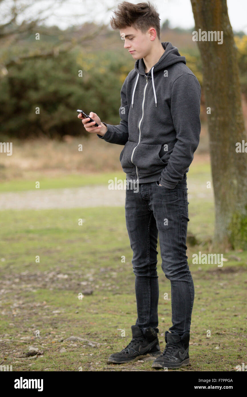 Teenager mit seinem Handy im freien Stockfoto