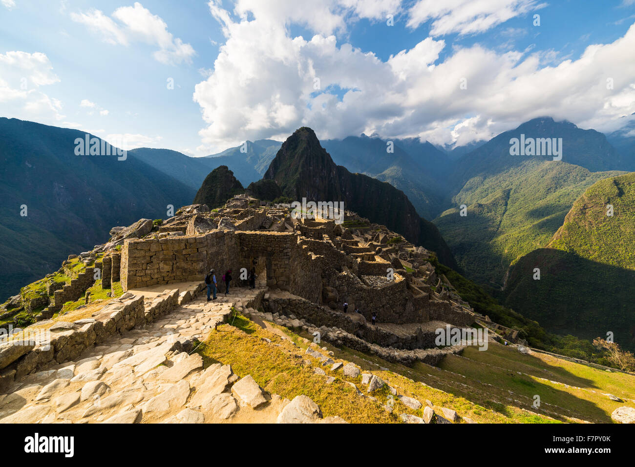 Machu Picchu teilweise durch das letzte Sonnenlicht beleuchtet. Weitwinkel-Blick von den Terrassen mit malerischen Himmel und leuchtende Pfad Stockfoto