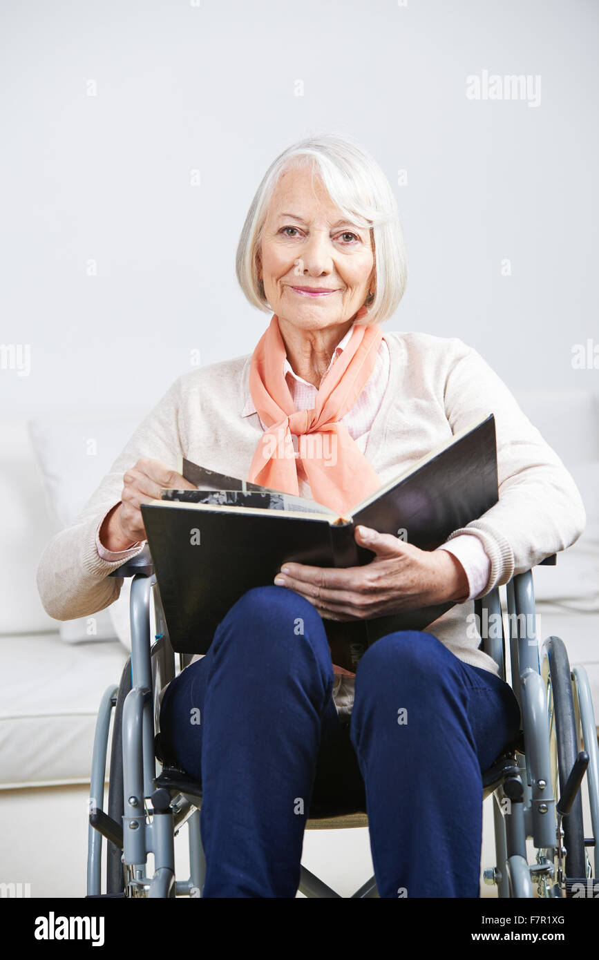 Alte Frau im Rollstuhl mit Fotoalbum zu Hause Stockfoto