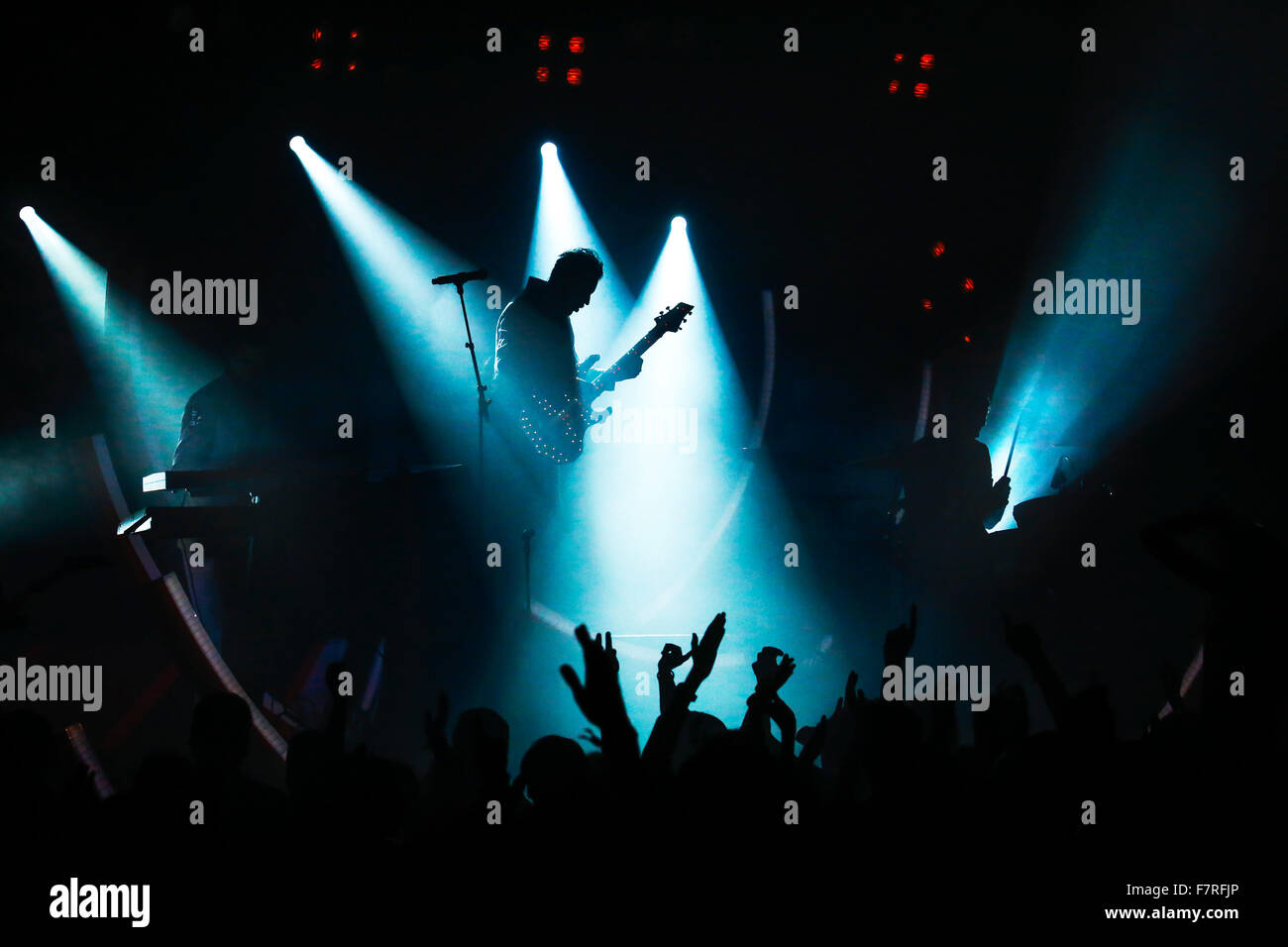 E-Gitarre Spieler von Rock Band in blau im Rampenlicht während Pop Konzert mit Silhouette der Masse Stockfoto