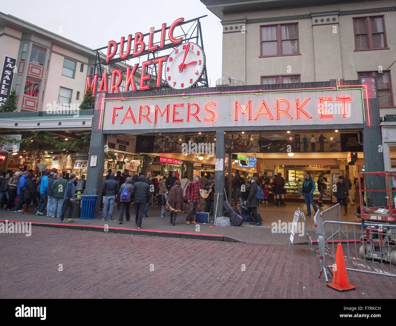 Seattle, Washington, USA. 23. November 2015. Pike Place Market in Seattle begann im Jahr 1907 und wurde entwickelt, um kleine Landwirte und Fischer sowie die Macher von anderen Gütern zu profitieren. Pike Place Market entlang der Waterfront Seattle entlang Elliott Bay gelegen und besteht aus nicht entlang Pike Place, einer Stadtstraße, aber auch mehrere Stockwerke unter sowie. Pike Place Market hat im Laufe der Jahre einige Veränderungen durchgemacht, aber behielt seinen Charme der alten Welt die Touristen aus der ganzen Welt. ---Auf dem Foto kündigt eine große Leuchtreklame neben einer großen Uhr Eingang zum Pike Place Market Stockfoto