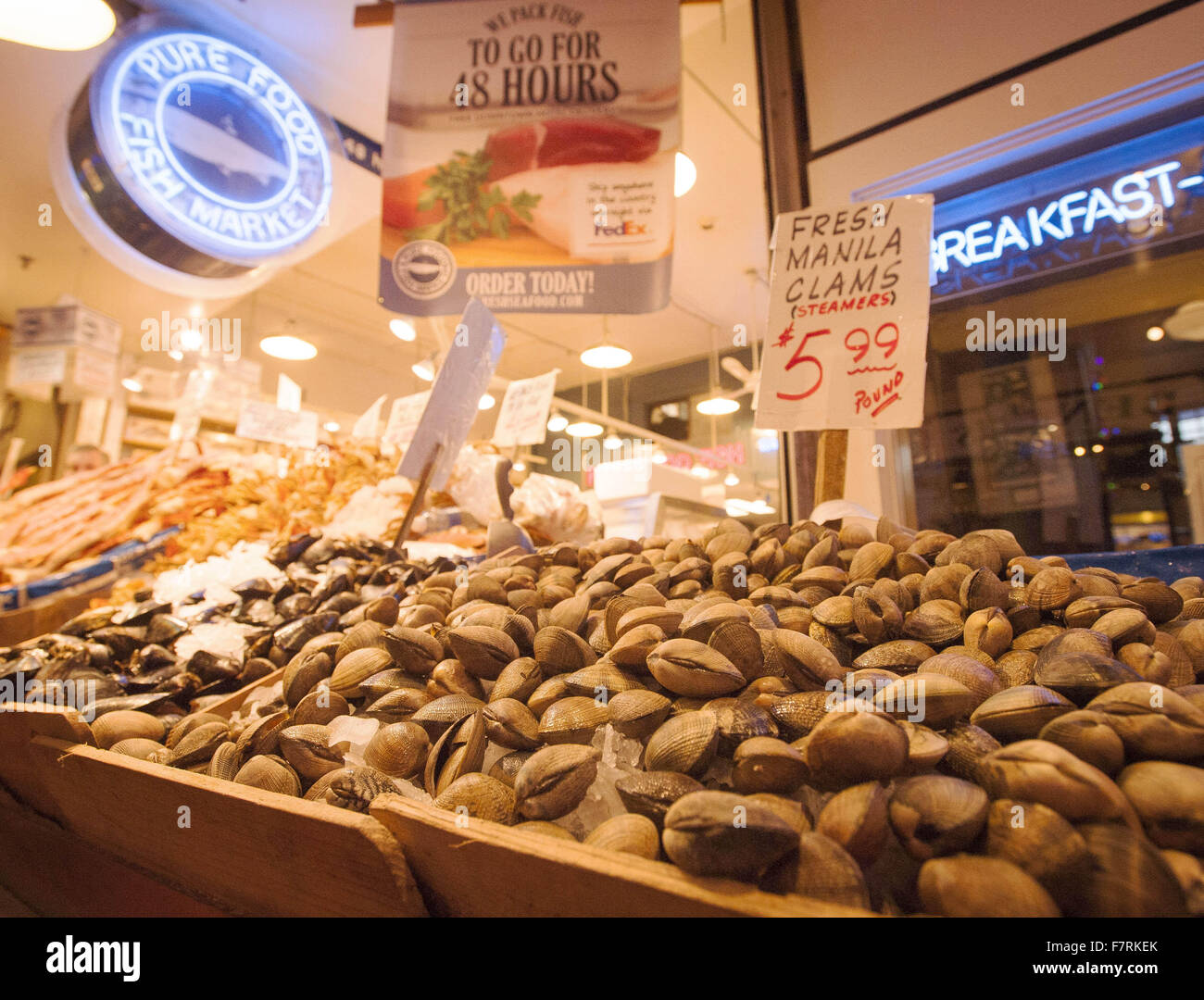 Seattle, Washington, USA. 23. November 2015. Pike Place Market in Seattle begann im Jahr 1907 und wurde entwickelt, um kleine Landwirte und Fischer sowie die Macher von anderen Gütern zu profitieren. Pike Place Market entlang der Waterfront Seattle entlang Elliott Bay gelegen und besteht aus nicht entlang Pike Place, einer Stadtstraße, aber auch mehrere Stockwerke unter sowie. Pike Place Market hat im Laufe der Jahre einige Veränderungen durchgemacht, aber behielt seinen Charme der alten Welt die Touristen aus der ganzen Welt. ---Auf dem Foto verkaufen in einem der mehreren Dutzend Stände, Fisch und andere Meeresfrüchte-Delikatessen, Manila Muschel Stockfoto