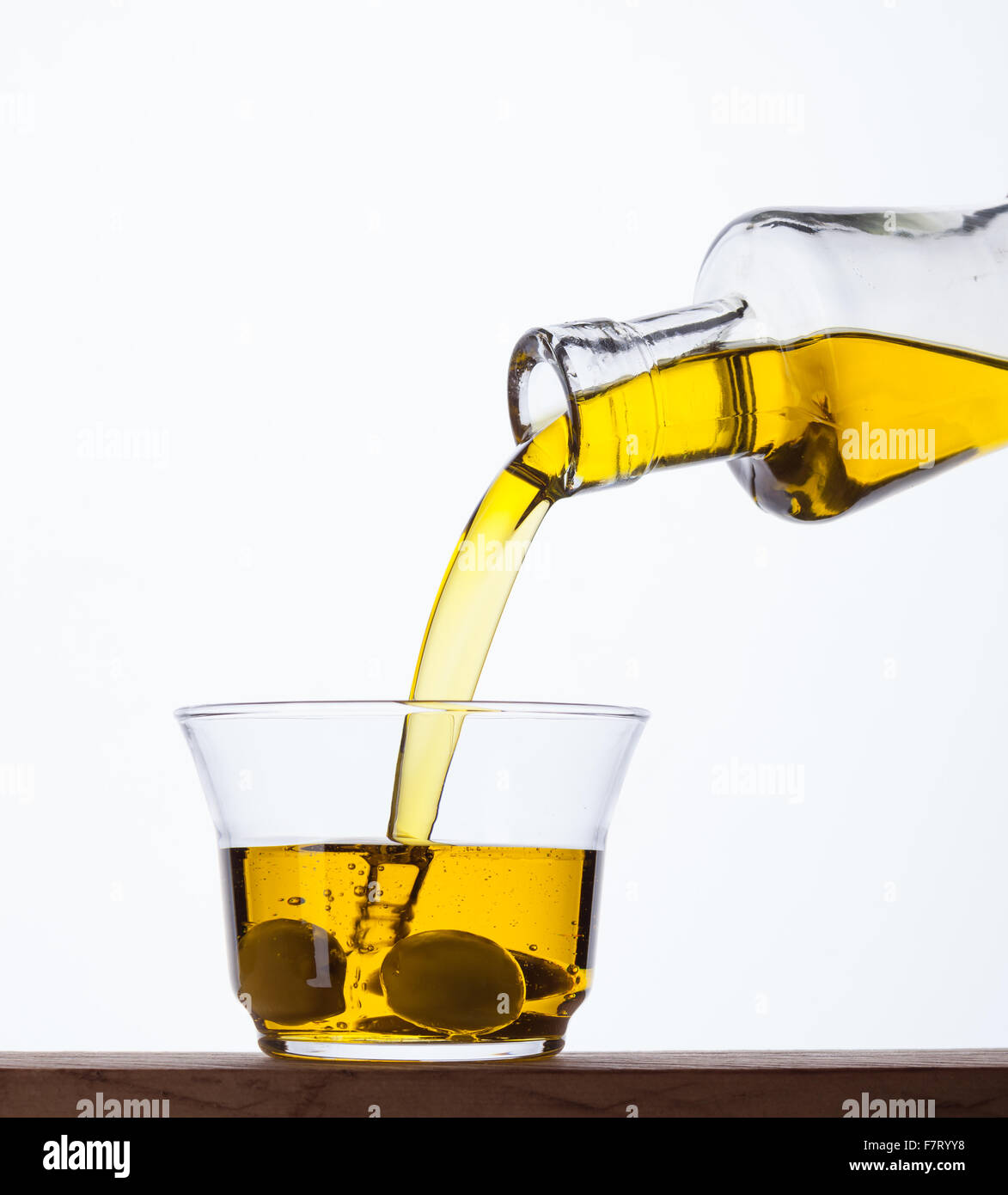 Olivenöl extra vergine aus der Flasche in ein Glas gegossen wird. Stockfoto