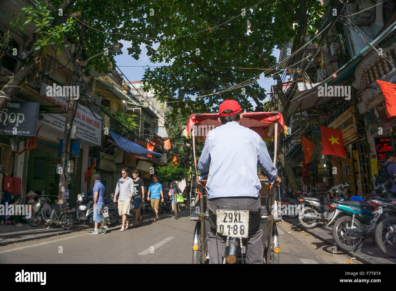 Hanoi, Vietnam: Ein Cyclo-Fahrer fährt vorbei an eine typische Straßenszene in lebendige Altstadt von Hanoi. Stockfoto