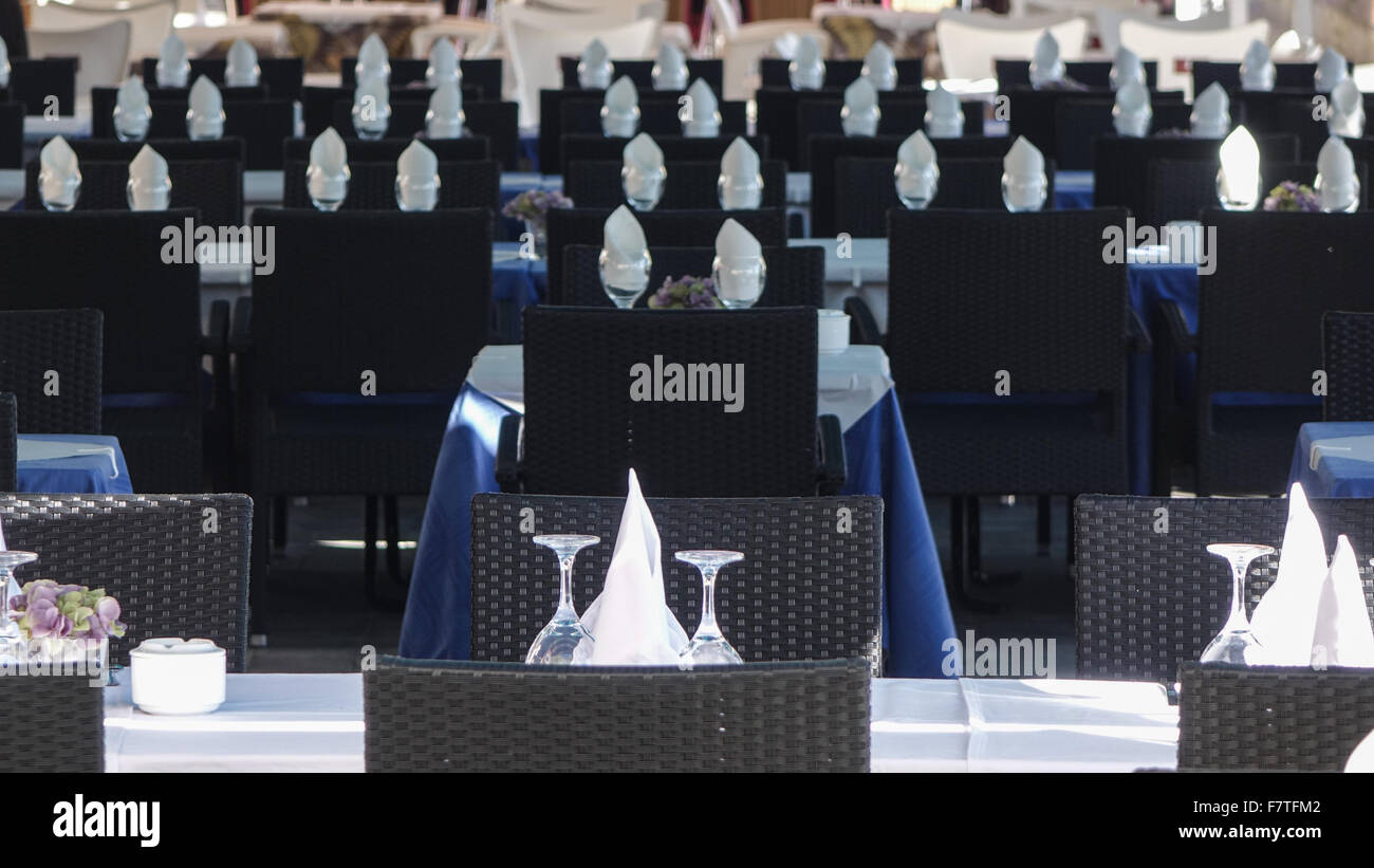 Weißes Leinen und umgedrehten Gläser auf Restaurant-Tische mit schwarzer Korbsessel in Vilajoyosa, Provinz Alicante, Spanien. Stockfoto