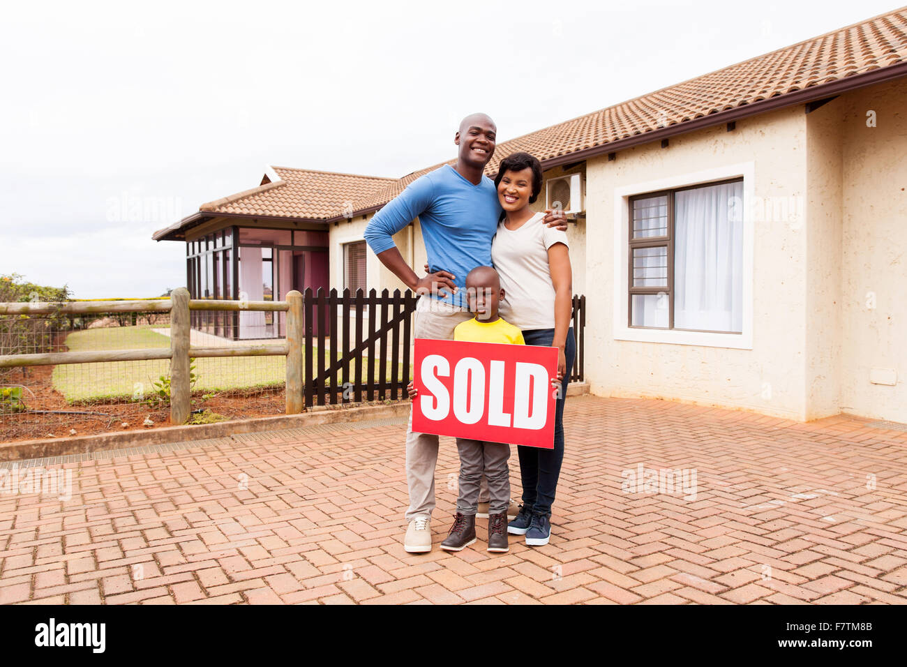 glückliche junge afrikanische Familie vor ihrem Haus mit verkauften Immobilien Schild Stockfoto