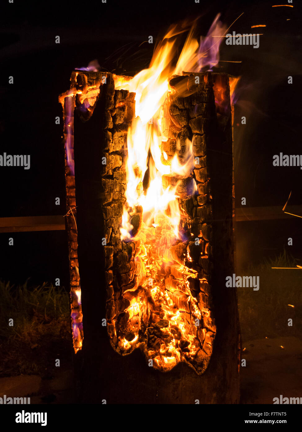 Schwedische Log Kerze brennt in der Nacht. Orange glühenden Glut und gelben Flammen. Stockfoto