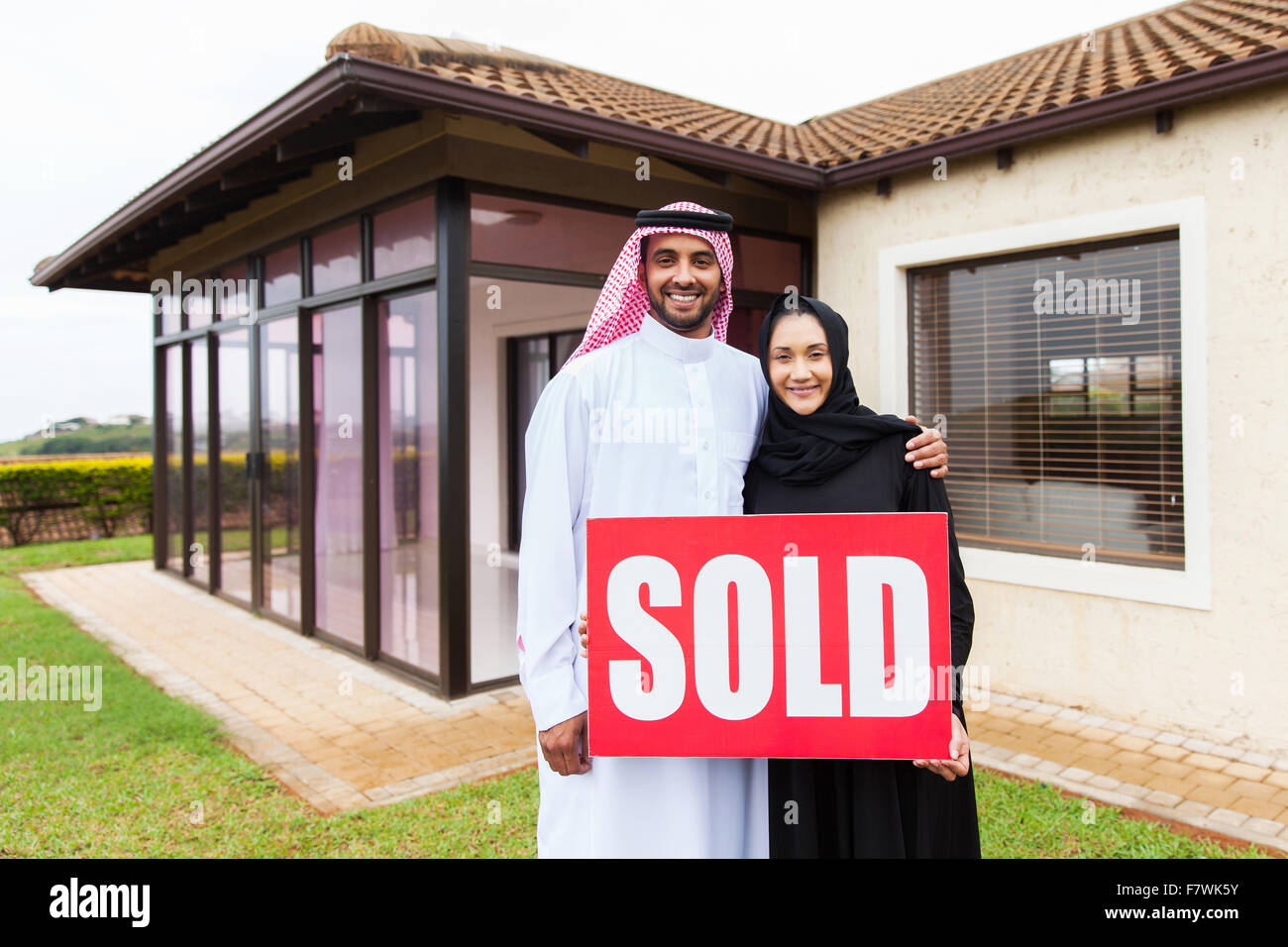 Arabische Brautpaar vor neuen Domizil mit verkauften Immobilien Schild Stockfoto