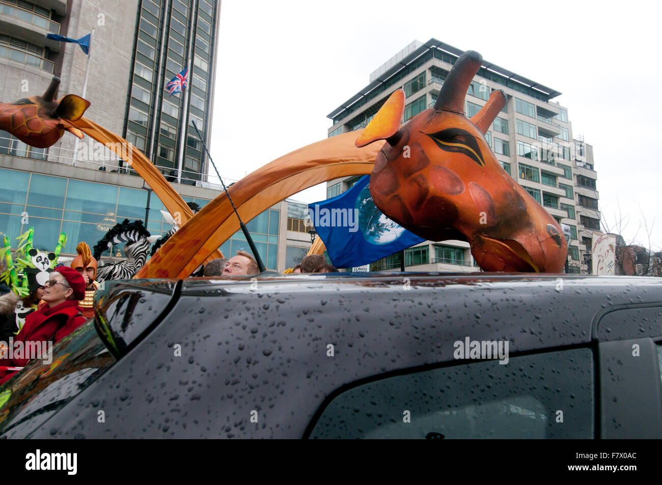 London, 29. November 2015. März auf Nachfrage Maßnahmen weltweite führenden zur Bekämpfung des Klimawandels. Eine Giraffe nimmt auf ein Auto. Stockfoto