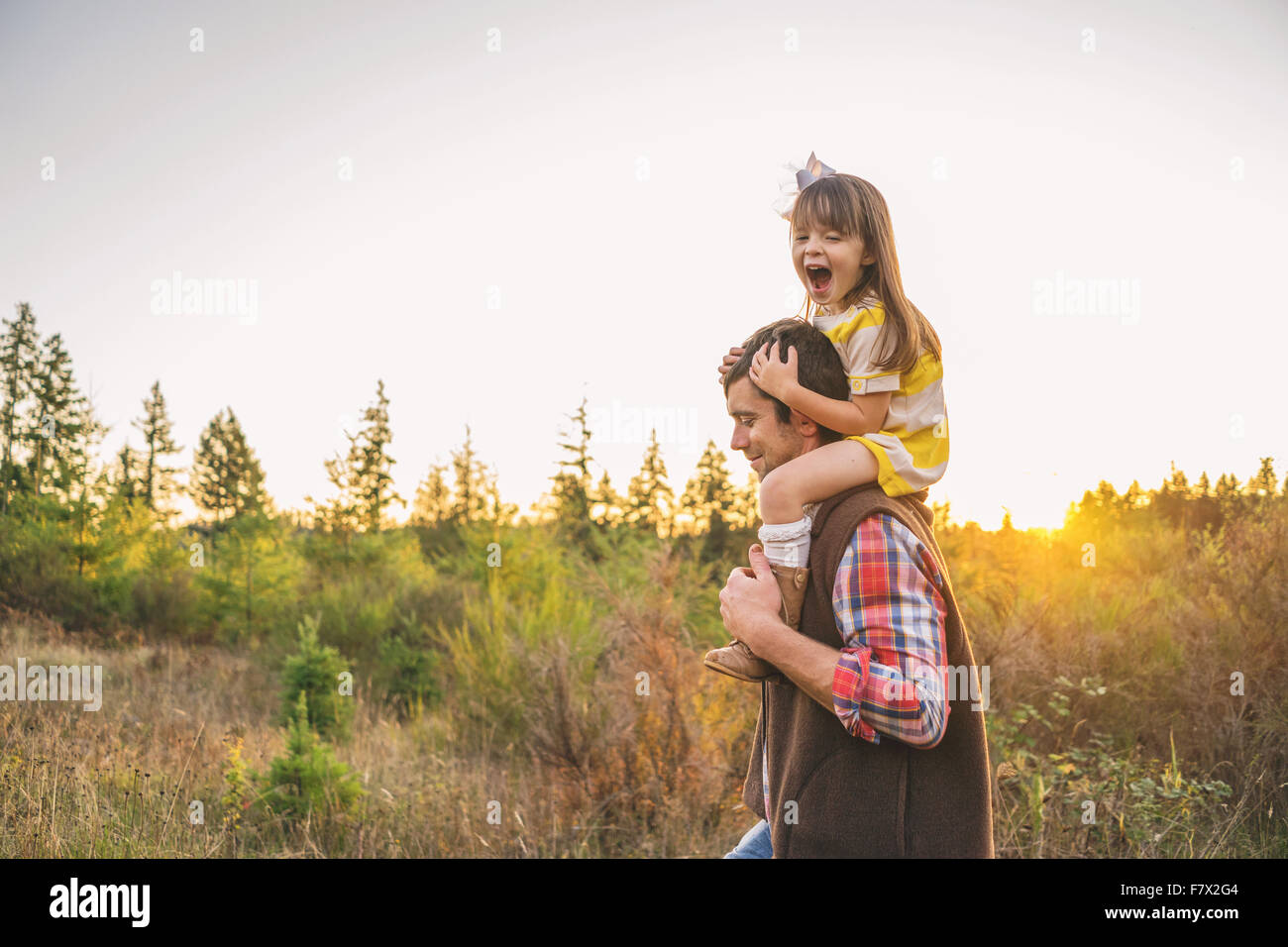 Vater mit Tochter auf den Schultern auf dem Lande Stockfoto