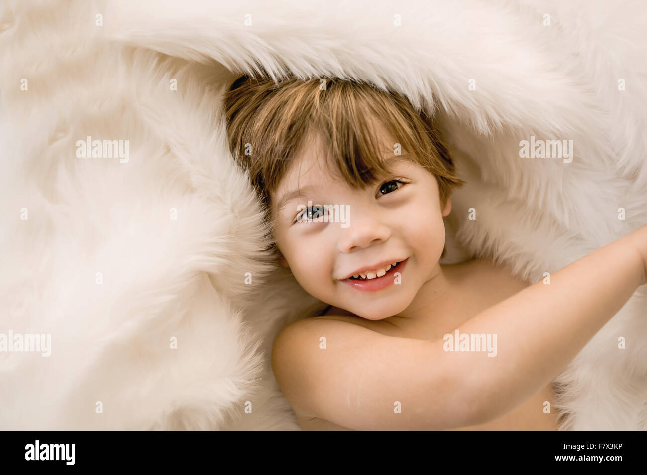 Portrait eines lächelnden jungen in einen Pelz-Wolldecke eingewickelt Stockfoto