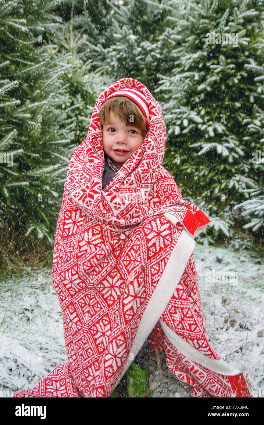 Junge draußen im Schnee, in Decke gehüllt Stockfoto