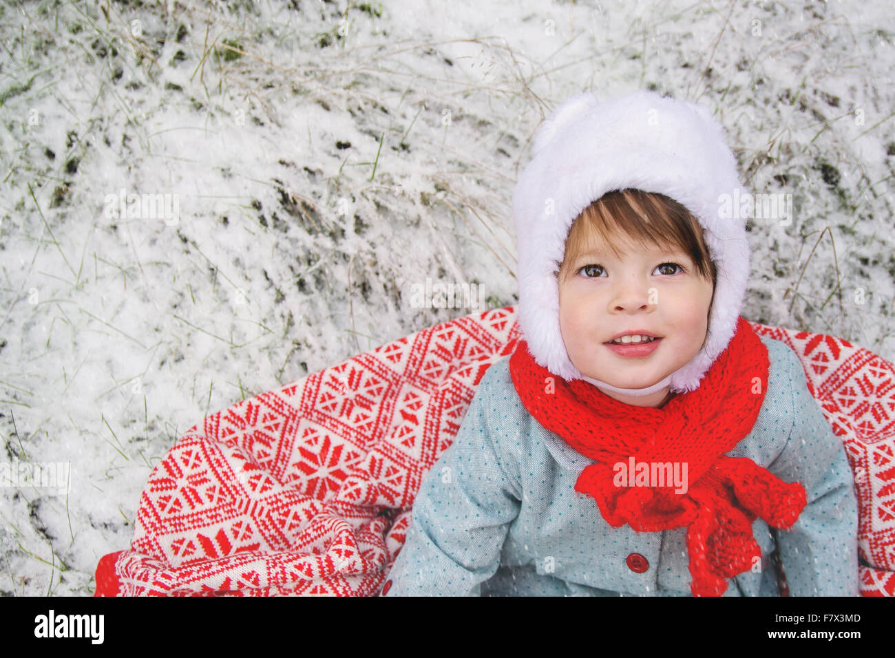 Mädchen sitzen auf einer Decke im Schnee Stockfoto