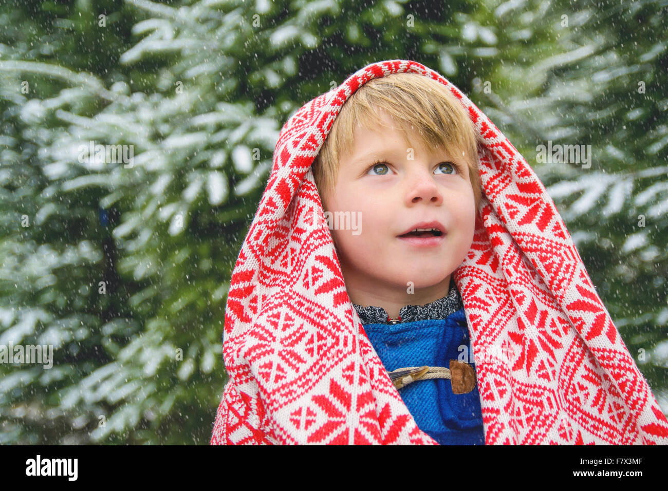 Junge, eingewickelt in eine Decke im Schnee nachschlagen Stockfoto