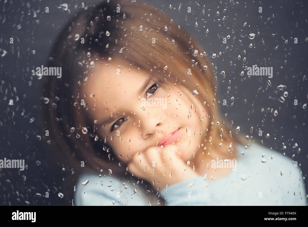 Blick aus einem Fenster an einem regnerischen Tag Mädchen Stockfoto