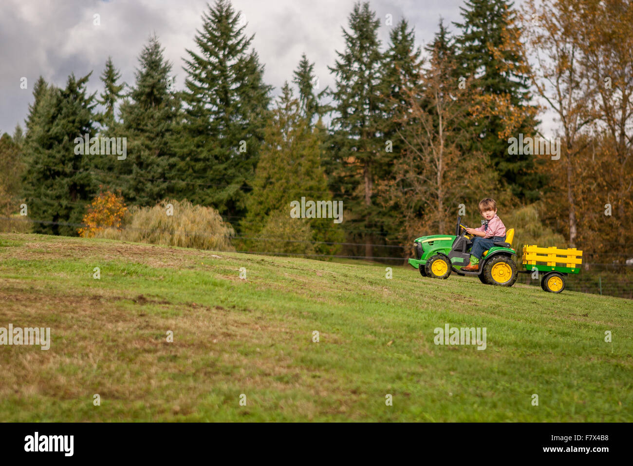 Junge einen Spielzeug-Traktor bergauf zu fahren Stockfoto