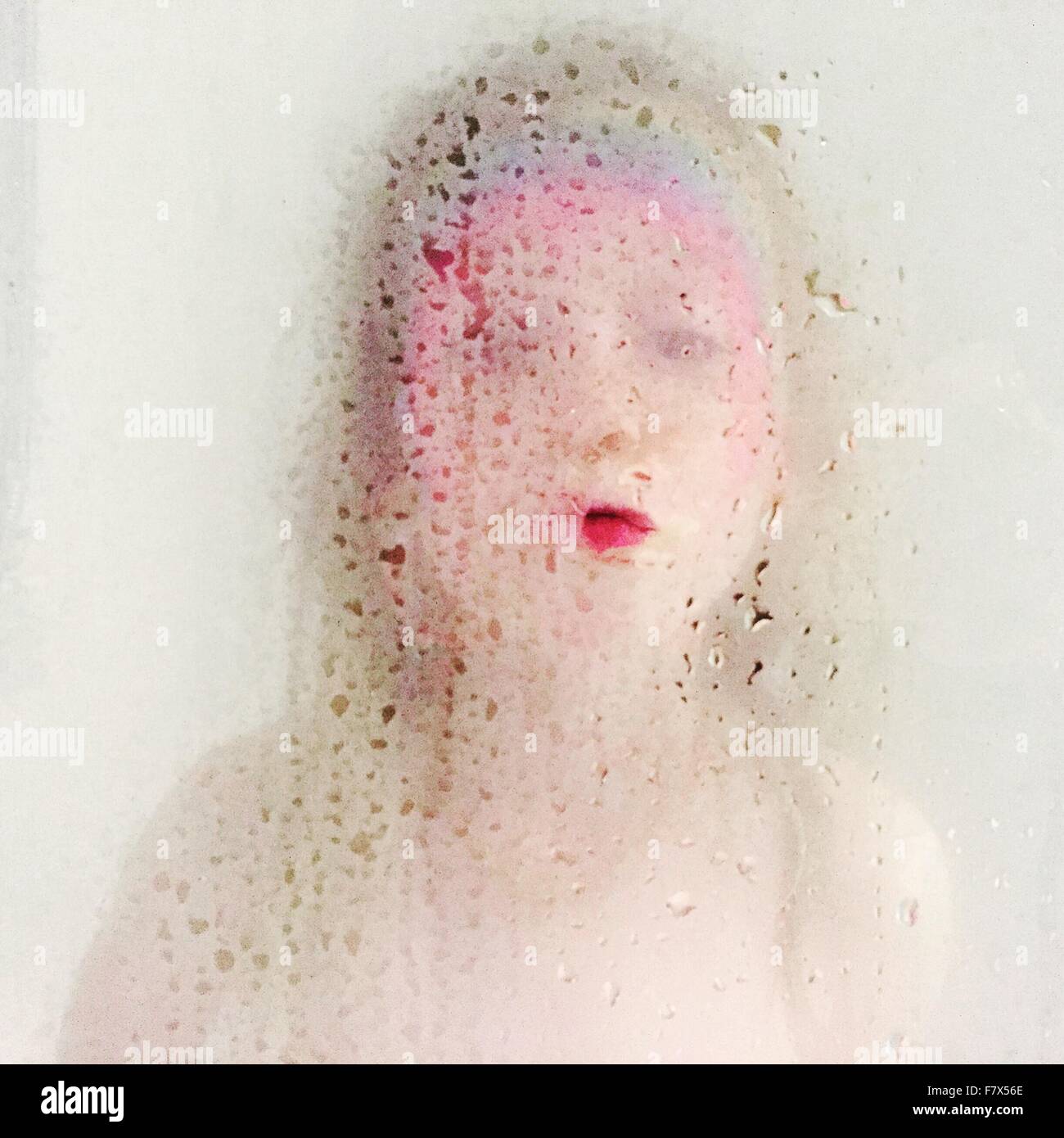Porträt des Kindes mit Regenbogen Gesicht hinter Duschtür print Stockfoto