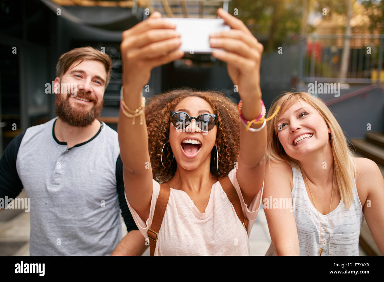 Gruppe von lächelnden Freunde nehmen Selfie mit Handy. Gemischtrassig Mann und Frauen amüsieren sich im Freien und unter pict Stockfoto