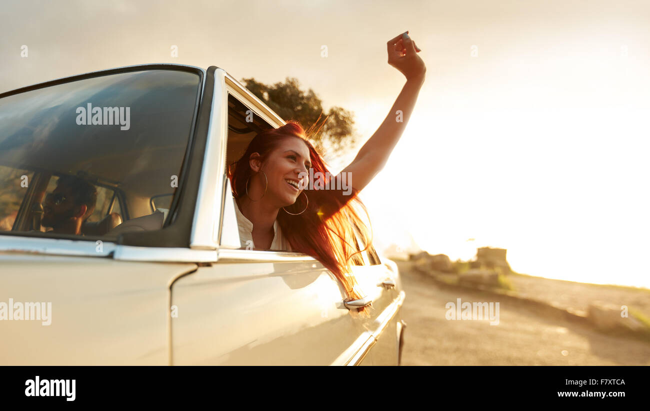 Schuss von schönen jungen Frau, die Reise an einem Sommertag zu genießen. Junge Frau hob ihre Hand aus dem Auto begeistert. Stockfoto