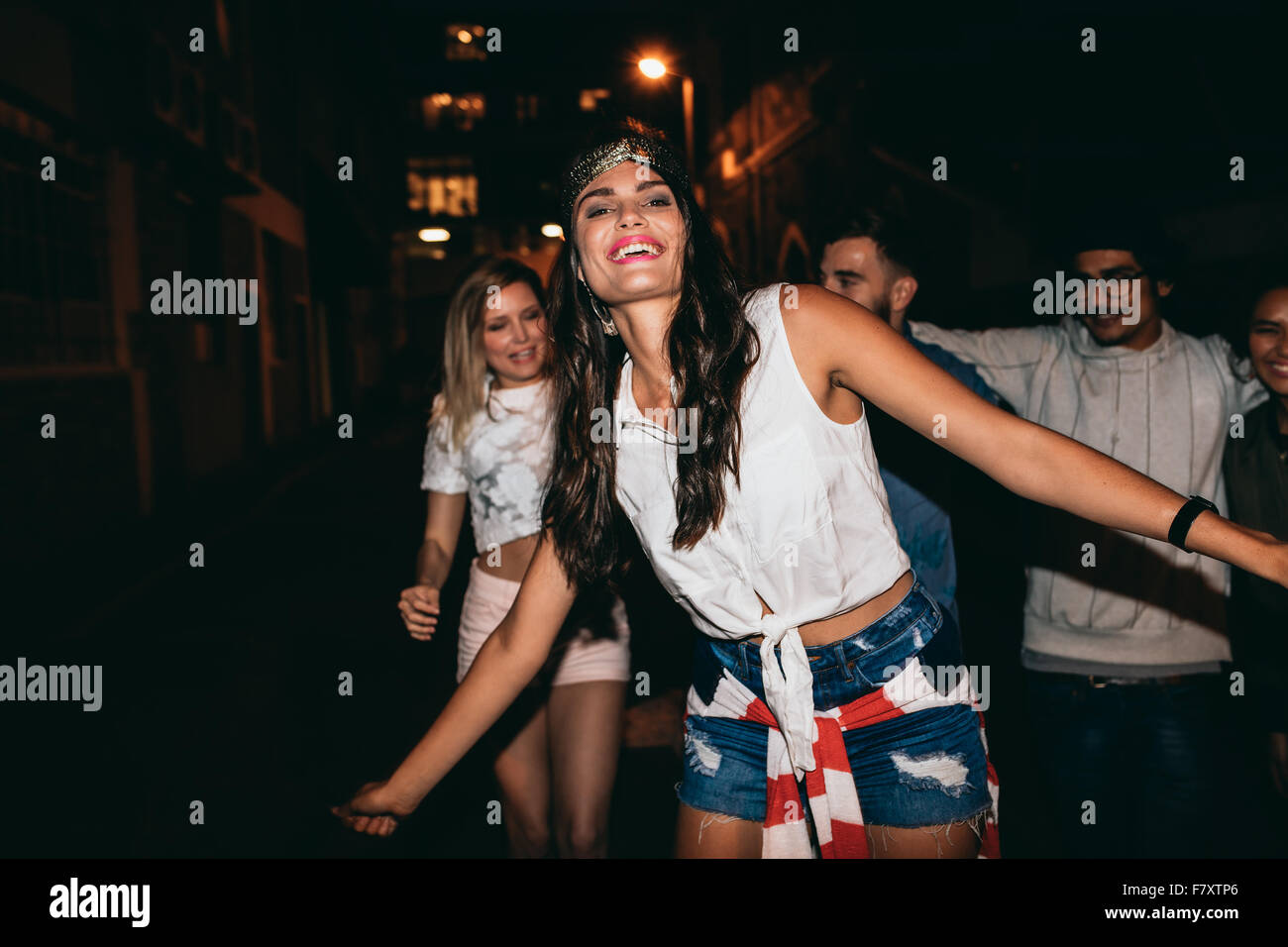 Porträt der schönen jungen Frau tanzen mit ihren Freundinnen im Hintergrund. Glückliche junge Frau in Party mit Freunden in der Nacht. Stockfoto