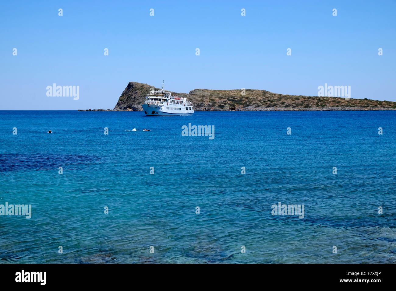 Touristenboot und Leute schwimmen im Meer auf der anderen Seite der Halbinsel Spinalonga, Crete. Stockfoto