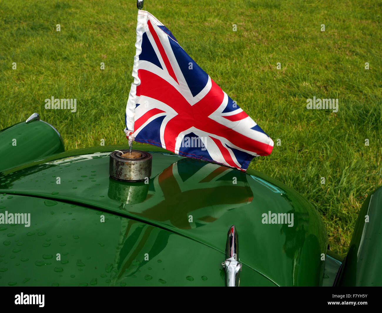 Union Jack-Flagge, die beim Start des grünen Oldtimer mit Gegenwartsgesellschaft in glänzenden Lackierung Stockfoto