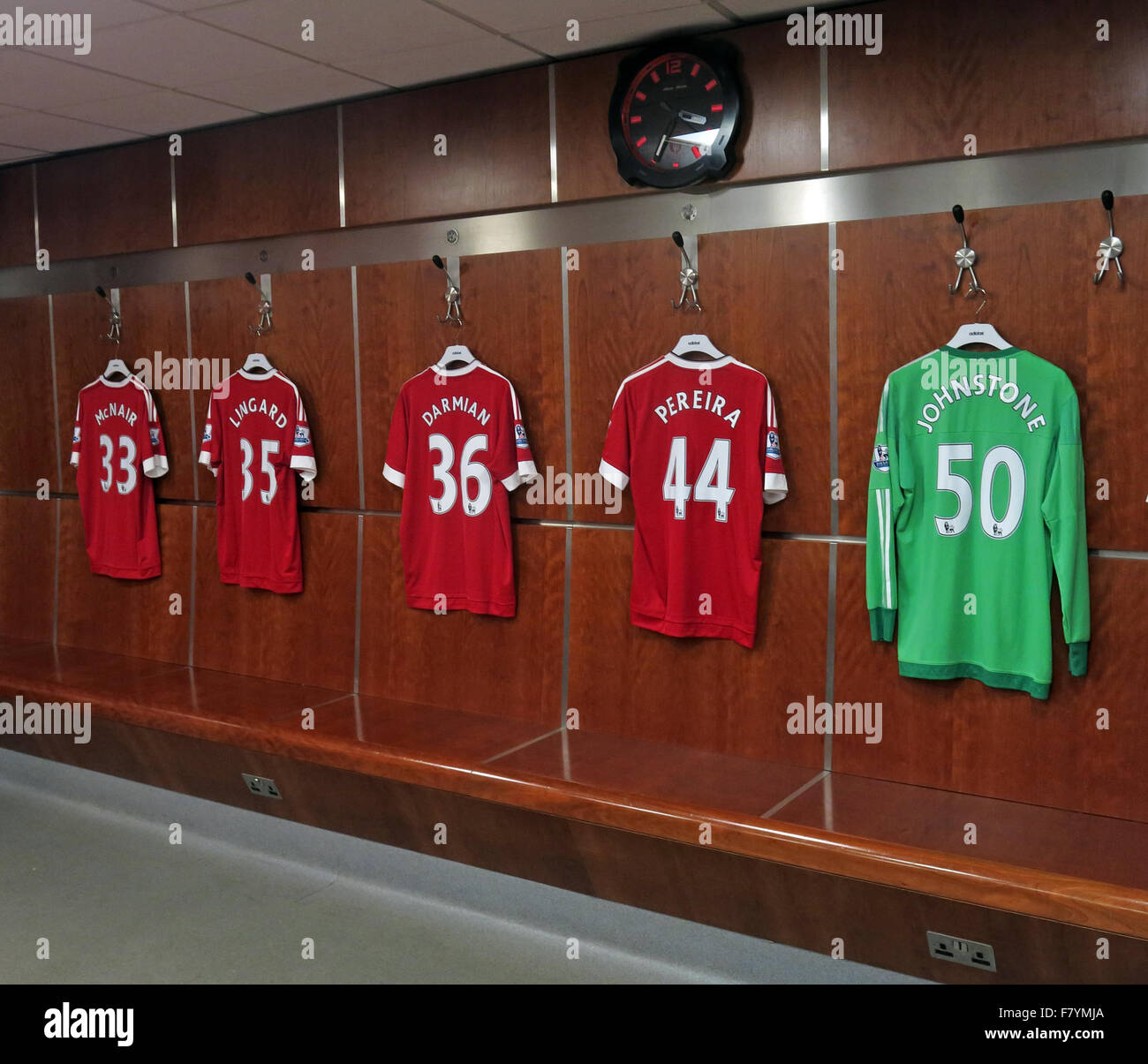 Mix von MUFC Hemden Aufhängen in MUFC Ankleidezimmer mit MUFC Uhr, Old Trafford, Manchester Stockfoto