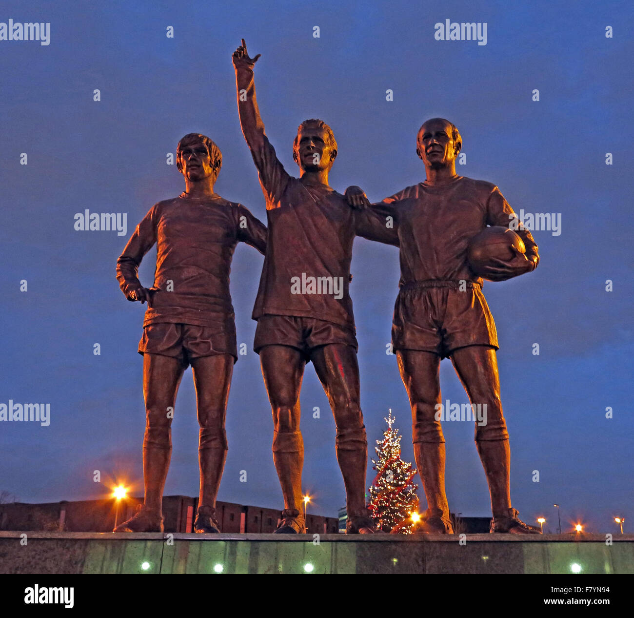 Vereinigte Trinity/Heilige Dreifaltigkeit Statue von Manchester United Trio von Bobby Charlton, George Best und Denis Law in der Abenddämmerung Stockfoto