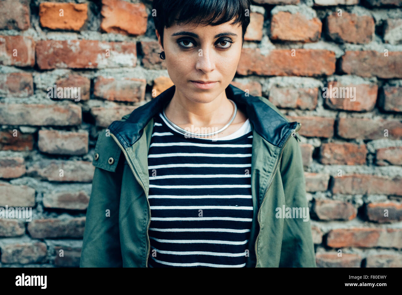 Halbe Länge des jungen schönen kaukasischen braun glattes Haar Frau posiert eine Wand gelehnt, auf der Suche in der Kamera, nachdenklich - ernst, durchdachtes Konzept Stockfoto