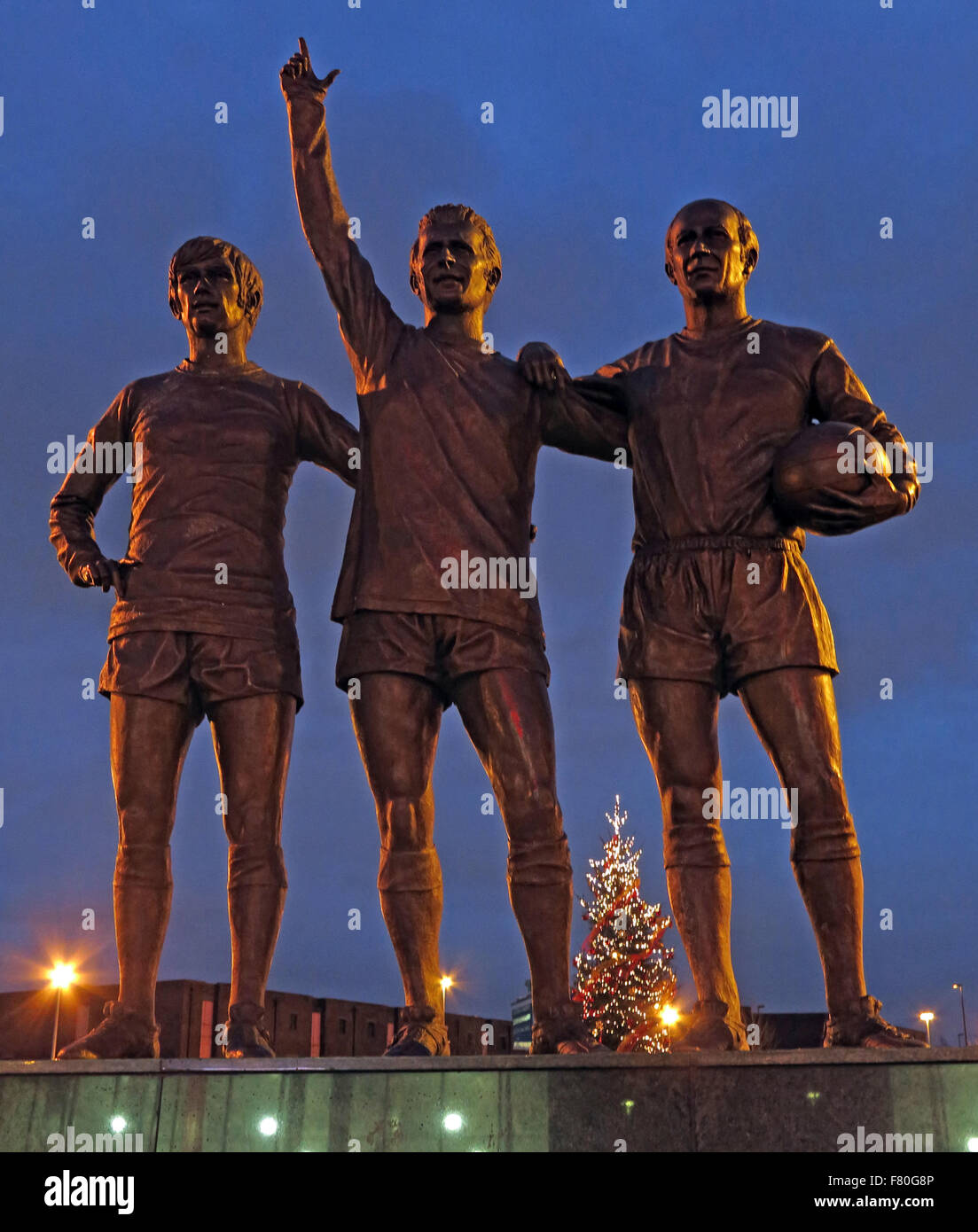 Vereinigte Trinity/Heilige Dreifaltigkeit Statue von Manchester United Trio von Bobby Charlton, George Best und Denis Law in der Abenddämmerung Stockfoto