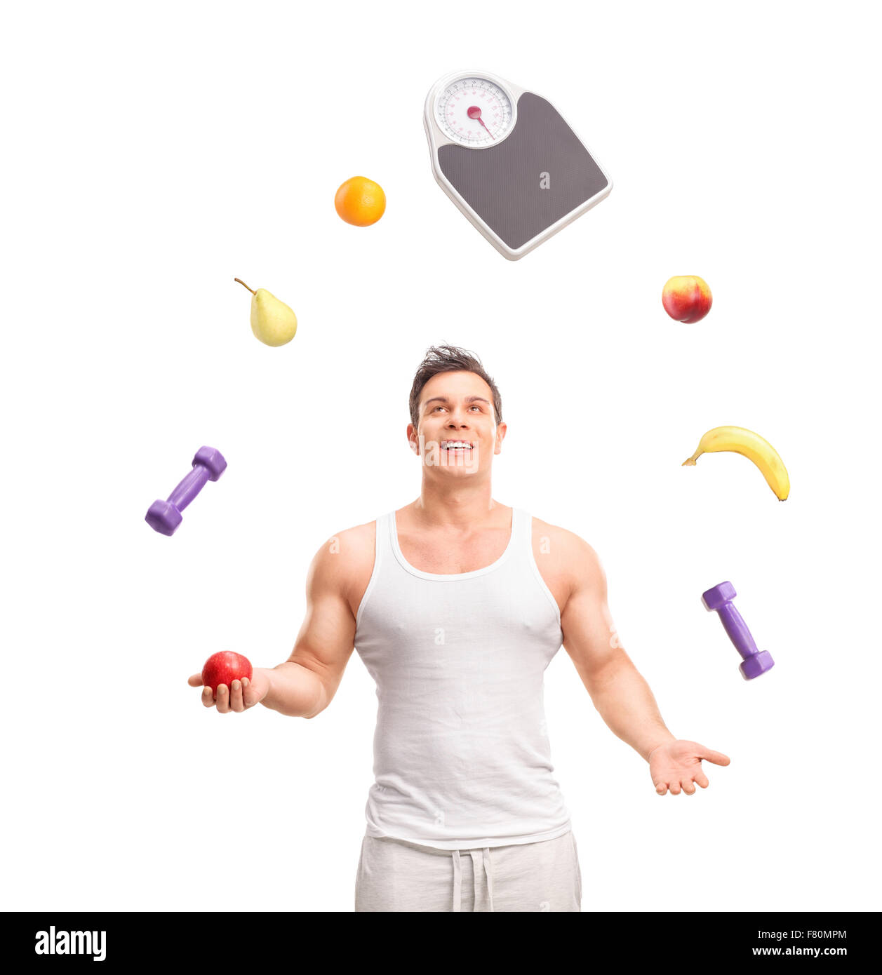 Hübscher junger Kerl Jonglieren mit verschiedenen Früchten und einem Gewicht skalieren isolierten auf weißen Hintergrund Stockfoto