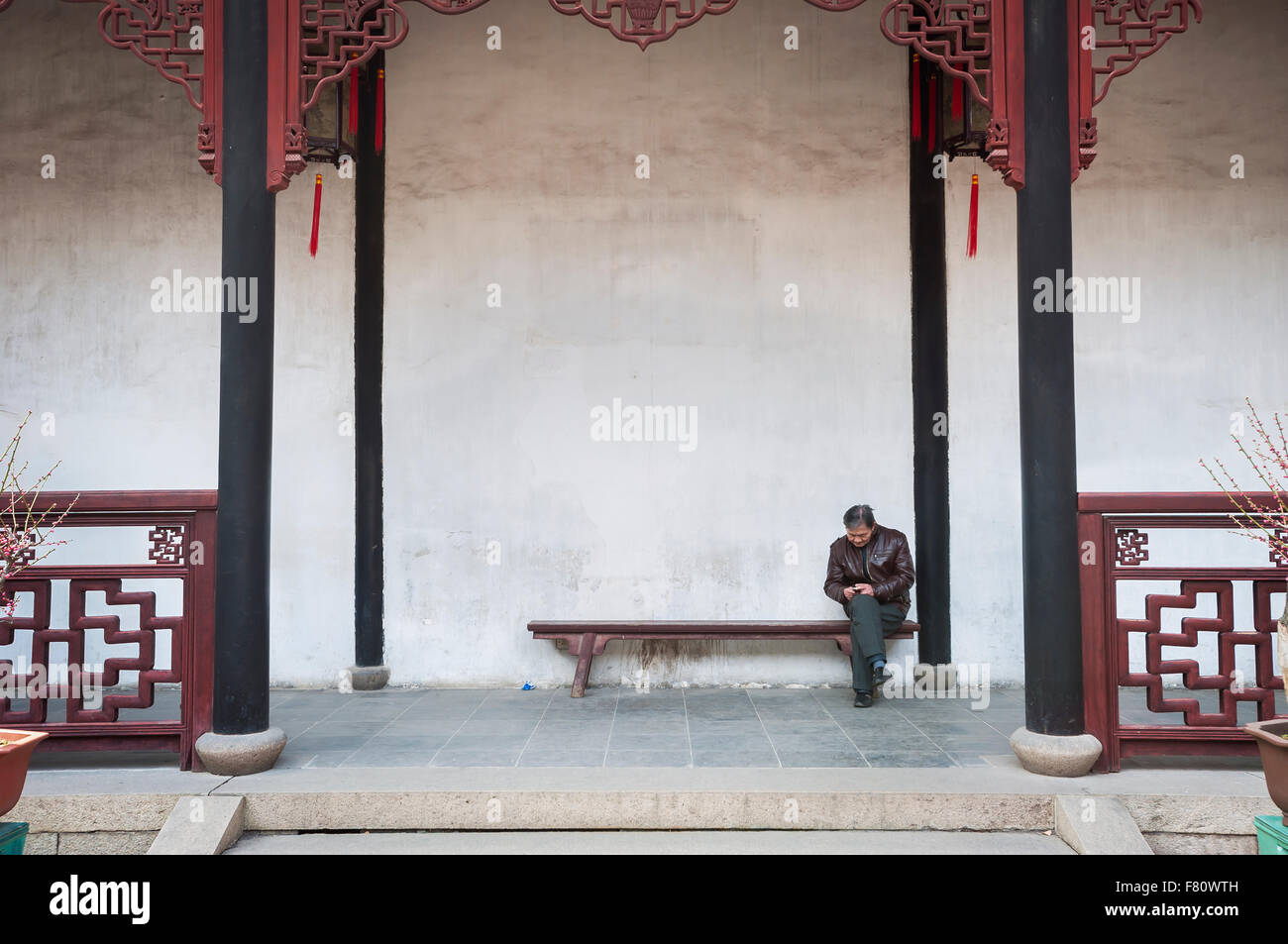 Chinesischer Tourist mit seinem Handy in der Löwe Grove Garden, Suzhou, China Stockfoto