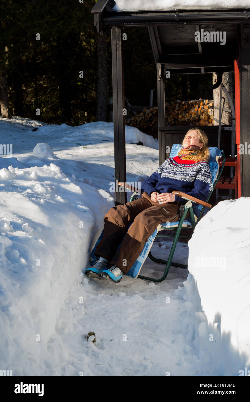 Junge hübsche norwegische Frau genießen einige Wintersonne, umgeben von Schnee in einem traditionellen norwegischen jumper Stockfoto