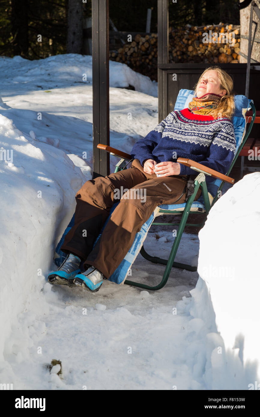 Nahaufnahme eines jungen ziemlich norwegische Frau genießen einige Wintersonne, umgeben von Schnee in eine traditionelle Norweger Stockfoto