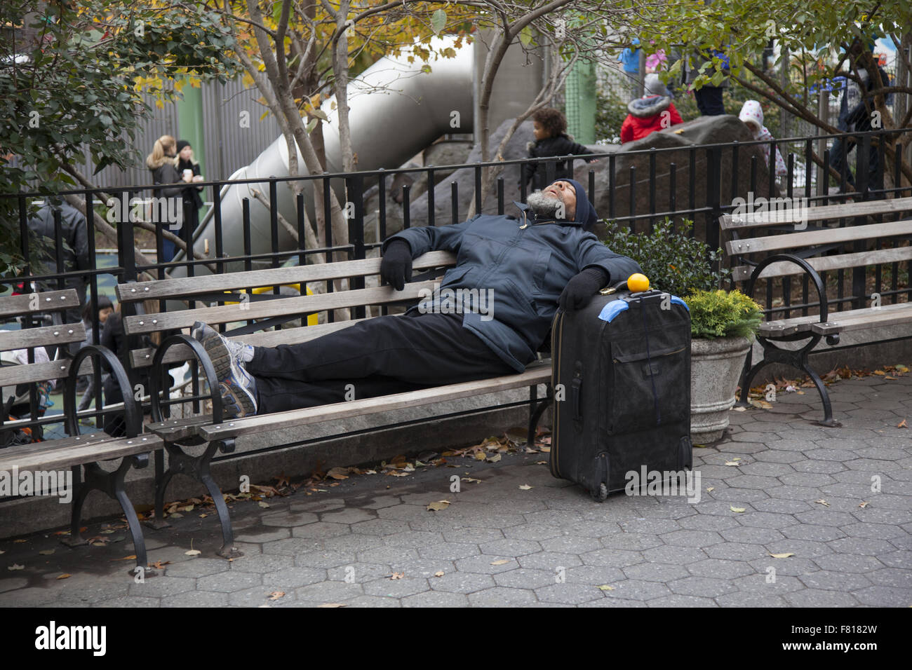 Mann schläft auf einer Bank im Union Square Park mit seinen Koffer an seiner Seite. New York City. Stockfoto