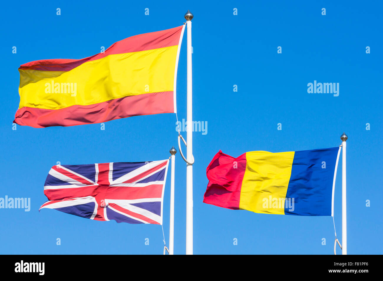 3 Flaggen, die rumänische Flagge spanische Flagge Union Jack Flagge gegen blauen Himmel Stockfoto