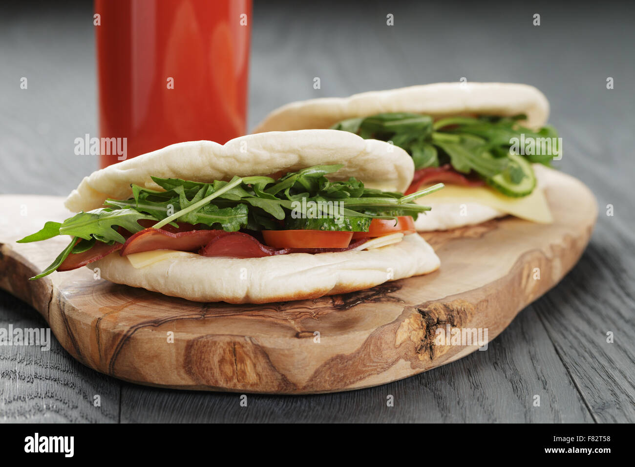 rustikale Sandwiches mit Schinken, Rucola und Tomaten im Fladenbrot auf Holztisch Stockfoto