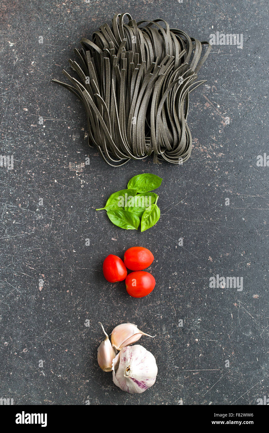 Nudeln, Knoblauch, Tomaten und Basilikum Blätter auf alten Küchentisch Stockfoto
