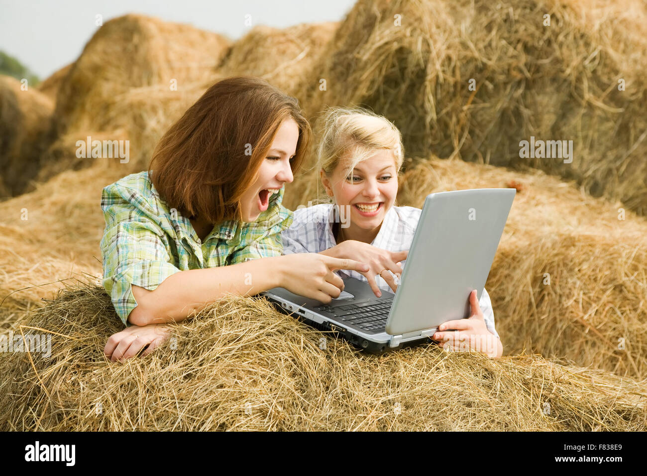 Glückliches Land Mädchen mit Laptop auf Heu im Feld Stockfoto
