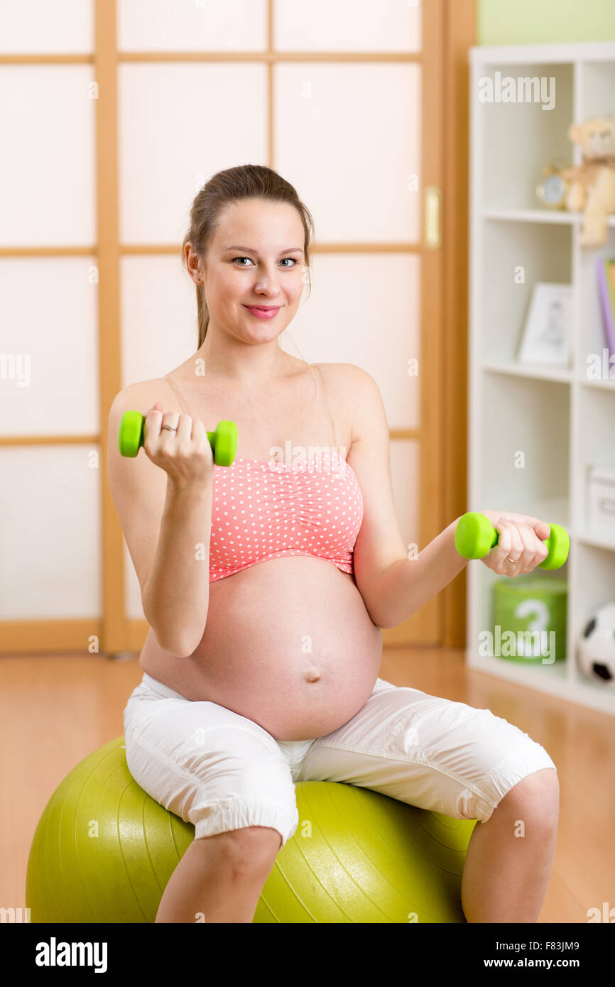 Schwangere Frau Fitness Übungen sitzen auf einem Gymnastikball mit Hanteln Stockfoto