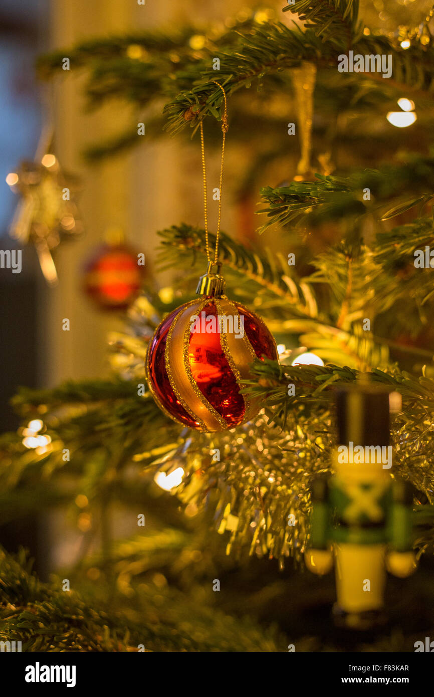 Ein Rubin rote Christbaumkugel und bunten, glänzenden, glitzernden Christbaumschmuck Sekt auf einer grünen Sitka-Fichte-Tanne Stockfoto