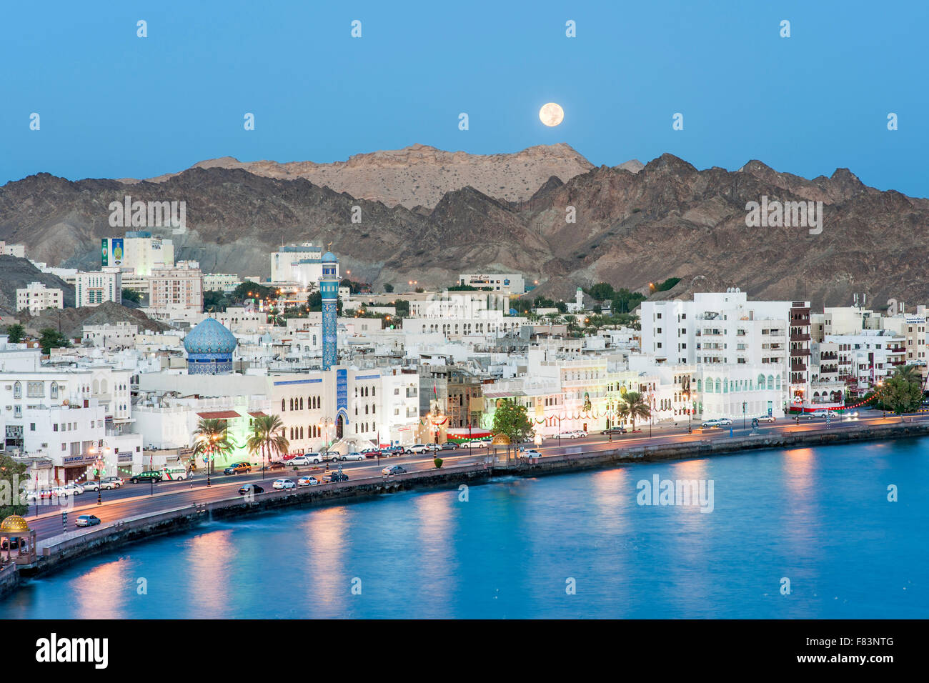 Dawn-Blick auf den Vollmond-Einstellung über den Stadtteil Mutrah und die umliegenden Berge in Muscat, der Hauptstadt des Sultanats Stockfoto