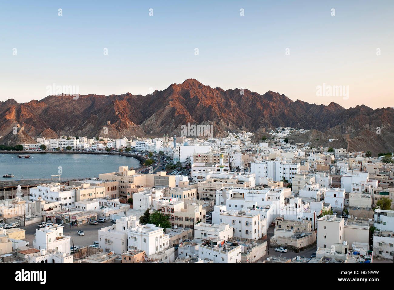 Abenddämmerung Blick auf den Stadtteil Mutrah und die umliegenden Berge in Muscat, der Hauptstadt des Sultanats Oman. Stockfoto